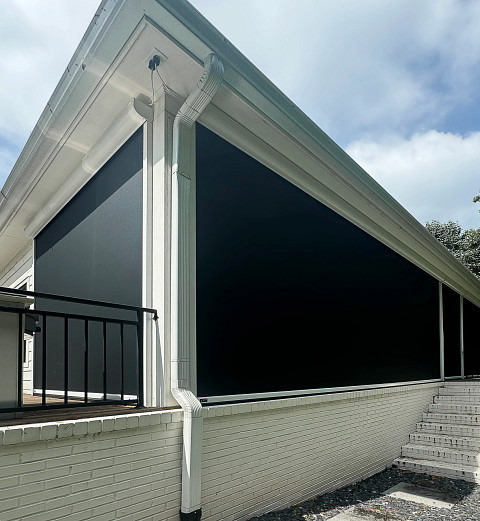 Motorized outdoor bug screens on white patio enclosure