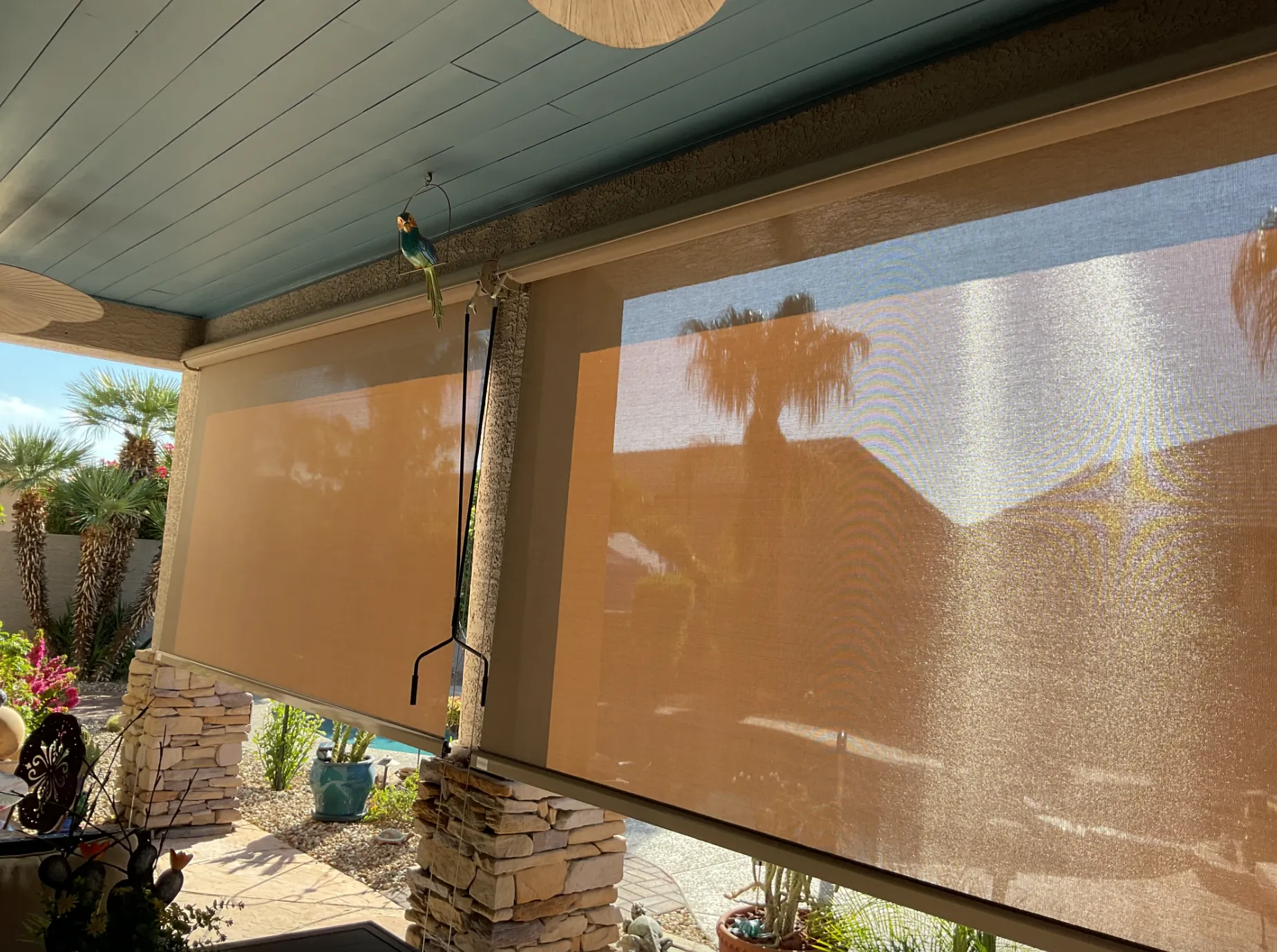 Retractable outdoor screen installed on a covered patio in a sunny backyard